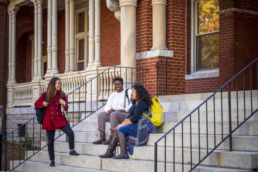 three students sitting on the steps of Main Hall